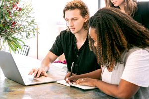 Two people taking notes from laptop